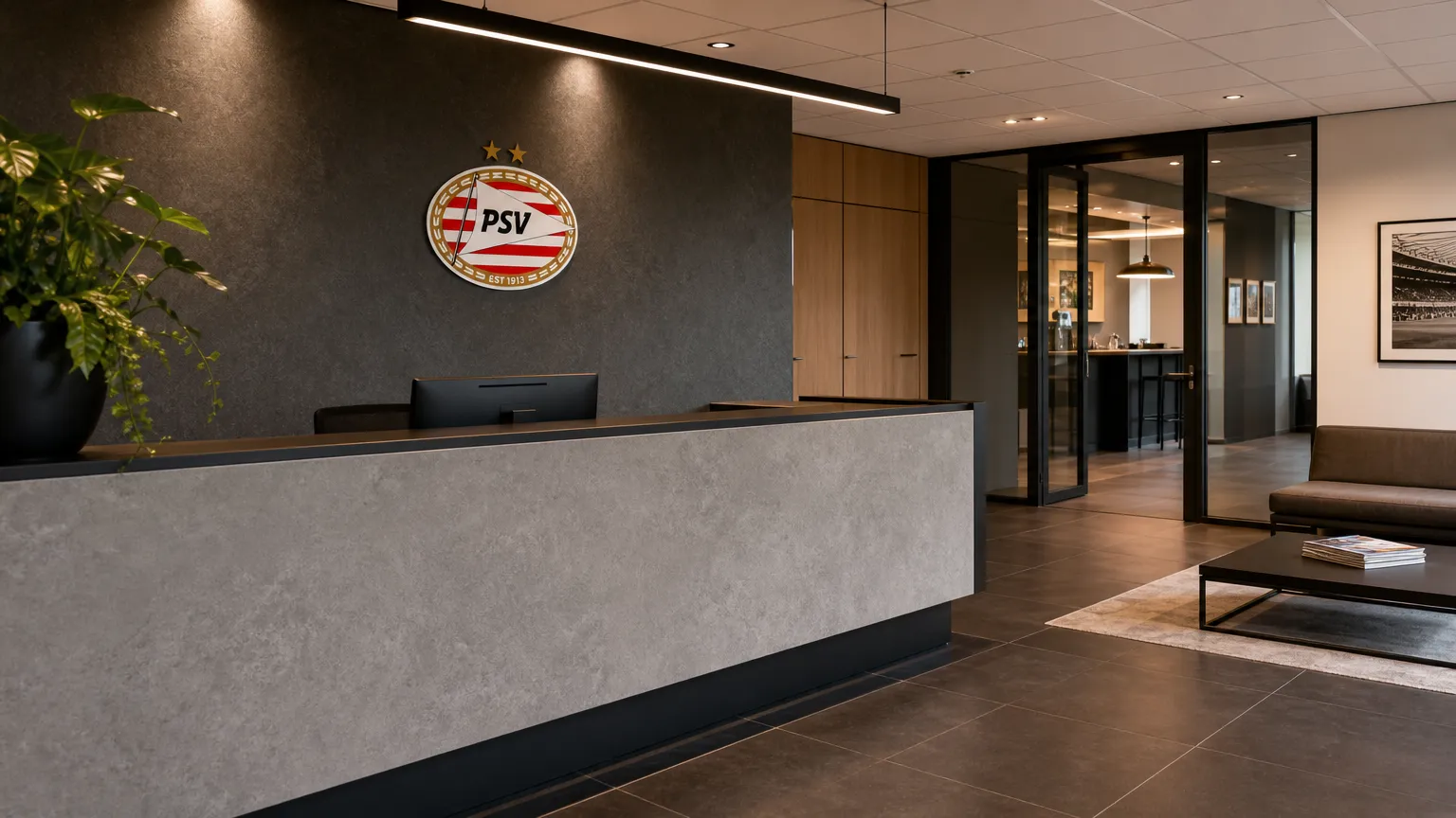 Een lege administratieve ontvangstruimte bij PSV met een discreet clubembleem aan de wand.