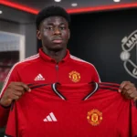 Carlos Baleba poseert met een Manchester United-shirt tijdens zijn officiële voorstelling.