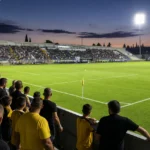 Open voetbalstadion in Cyprus met supporters dicht bij het speelveld voor de aftrap.