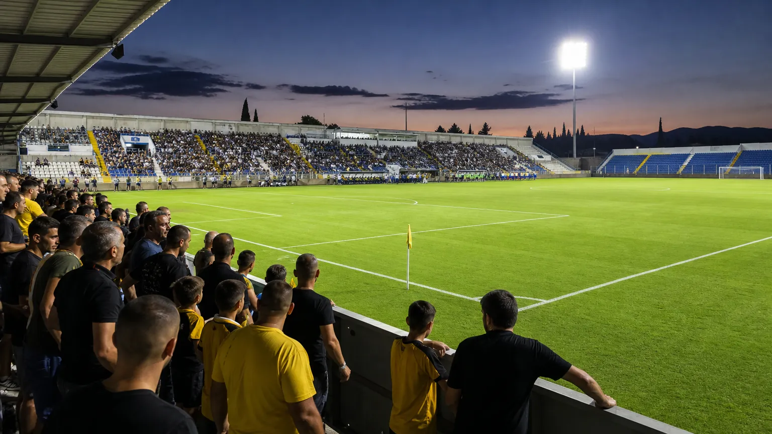 Open voetbalstadion in Cyprus met supporters dicht bij het speelveld voor de aftrap.