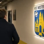 Een niet-herkenbare clubmedewerker in een gang met een KVC Westerlo-wandbord.