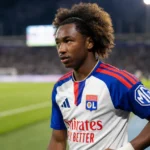 Malick Fofana in Lyon-tenue aan de rand van een voetbalveld.