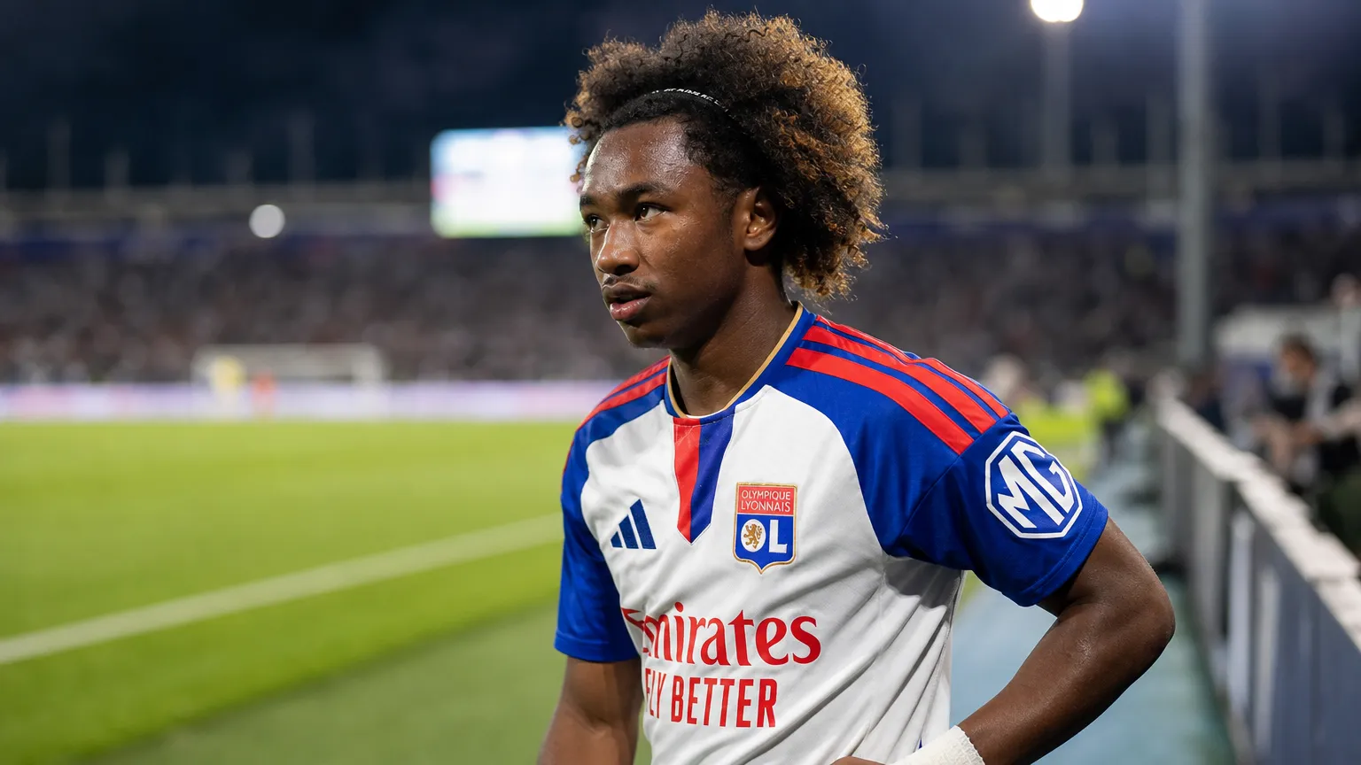 Malick Fofana in Lyon-tenue aan de rand van een voetbalveld.