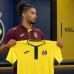 Nathan Saliba poseert met een Villarreal-shirt tijdens een officiële clubpresentatie.