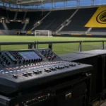 Bedieningspaneel voor het stadiongeloid in het stadion van Bodø/Glimt met een clubvlag op de achtergrond.