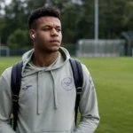 Kaye Furo in grijze Brentford-kleding aan de rand van een voetbalveld.