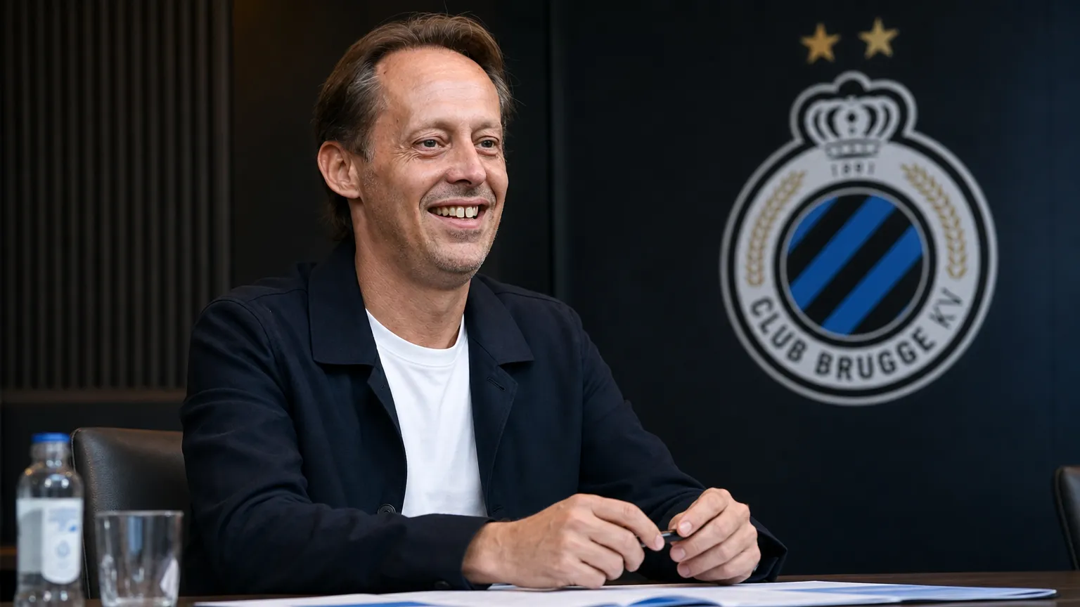 Een clubvertegenwoordiger van Club Brugge in een zakelijke voetbalomgeving.