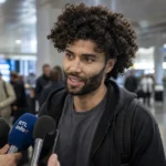 César Huerta spreekt journalisten toe in een luchthavenhal.