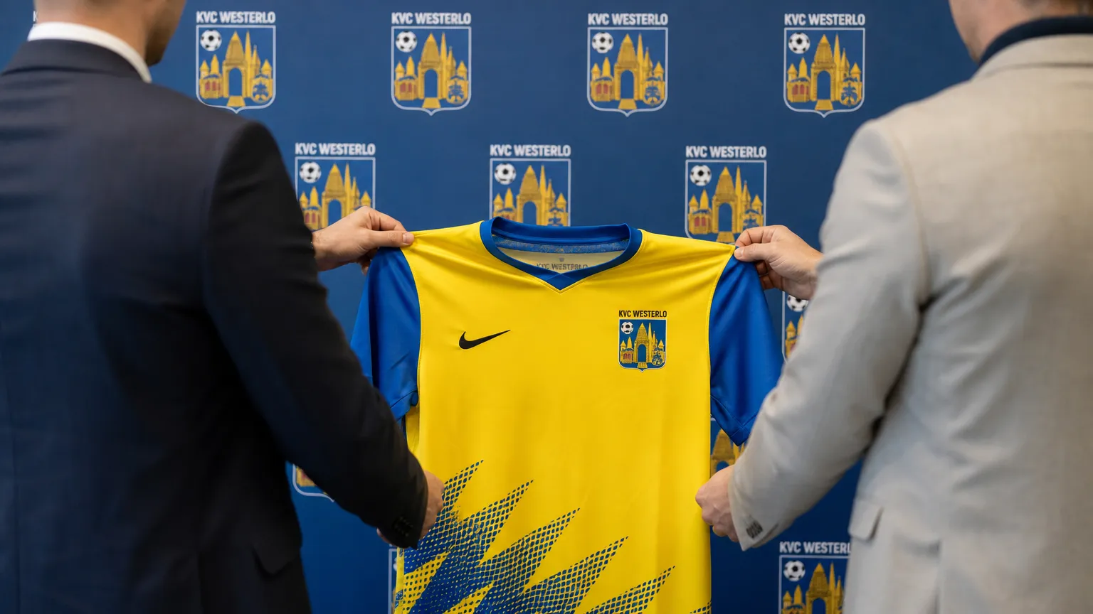 Niet-herkenbare clubvertegenwoordigers presenteren een KVC Westerlo-shirt in een officiƫle ruimte.