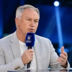 Marc Degryse spreekt met een microfoon in een televisiestudio.