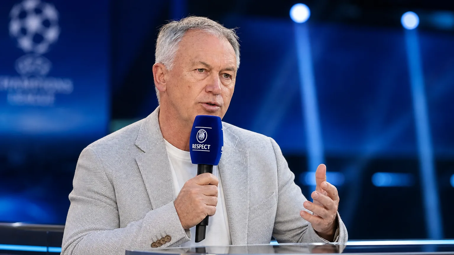 Marc Degryse spreekt met een microfoon in een televisiestudio.