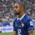 Bradley Barcola staat in een donkerblauw nationaal tenue langs het veld in een voetbalstadion.