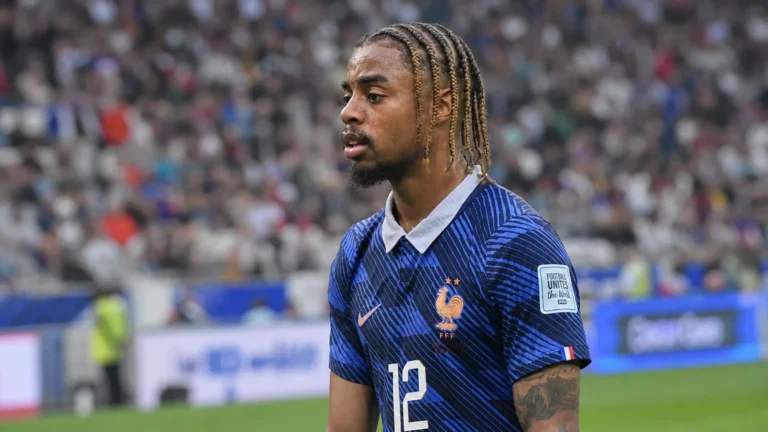 Bradley Barcola staat in een donkerblauw nationaal tenue langs het veld in een voetbalstadion.