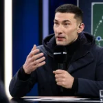 Silvio Proto spreekt met een microfoon tijdens een voetbalanalyse in een televisiestudio.