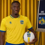 Pape Diong poseert tijdens zijn officiële voorstelling bij KVC Westerlo in een geel shirt.