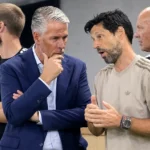 Vier clubmedewerkers in gesprek in een indoor voetbalomgeving.
