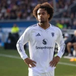Joshua Zirkzee in een wit Manchester United-tenue langs de rand van het veld.