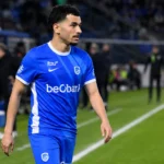 Zakaria El Ouahdi in blauw-wit voetbalshirt langs de zijlijn van een stadion