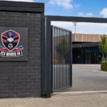 Ingang van het clubcomplex van FCV Dender EH met een discreet clubembleem.