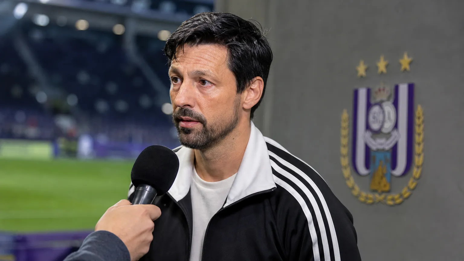 Vítor Bruno spreekt geconcentreerd in de interviewzone van een stadion.