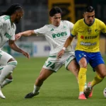 Drie voetballers strijden om de bal tijdens een Europese wedstrijd.