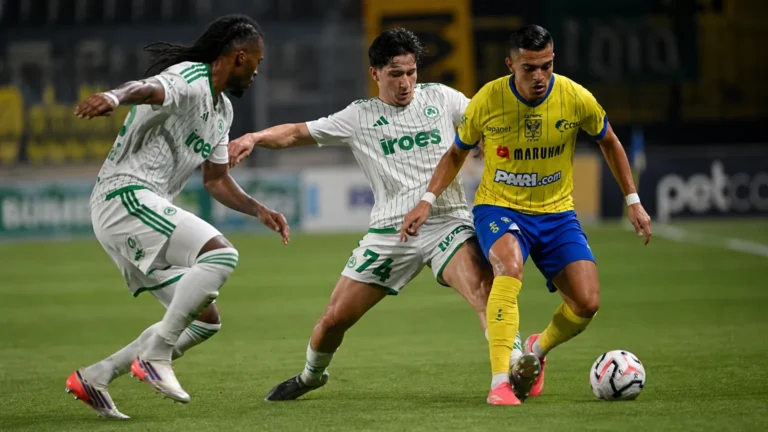 Drie voetballers strijden om de bal tijdens een Europese wedstrijd.