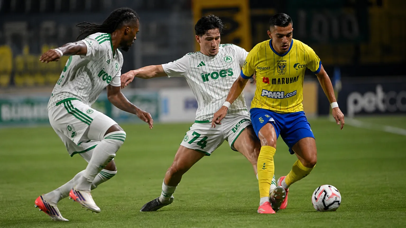 Drie voetballers strijden om de bal tijdens een Europese wedstrijd.