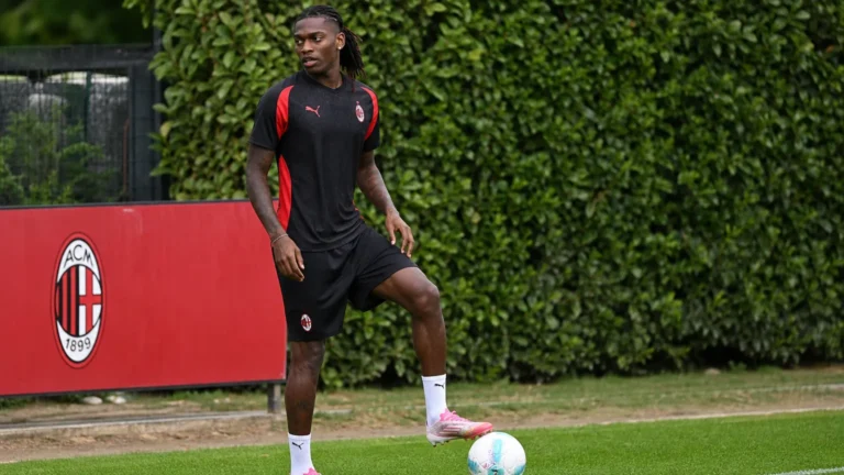 Rafael Leão in AC Milan-trainingskleding met een bal aan de rand van een voetbalveld.