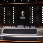 Een Europa League-lotingsstudio met een officieel wedstrijdbord op de achtergrond.