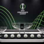 Een Conference League-lotingspodium met genummerde balletjes in een officiële zaal.