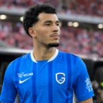 Zakaria El Ouahdi in het blauwe shirt van KRC Genk aan de zijlijn van een stadion.