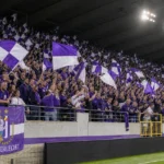 Supporters van RSC Anderlecht met paars-witte vlaggen op de tribune van het Lotto Park.