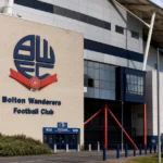De ingang van het stadion van Bolton Wanderers met een discreet clubbord.