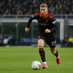 Ignace Van der Brempt in zwart-oranje tenue tijdens een voetbalactie met de bal.