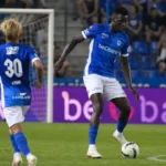Twee voetballers in blauw-witte tenues tijdens een aanval in een Belgisch voetbalstadion.