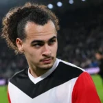 Arthur Theate in zijn voetbaltenue aan de rand van het veld.