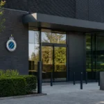 Ingang van het clubgebouw van Club Brugge met een discreet clubembleem aan de gevel.