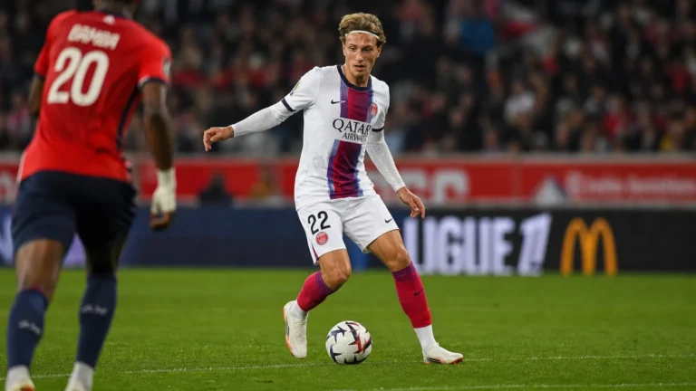 Mika Godts in een wit PSG-tenue tijdens een wedstrijdactie met de bal.