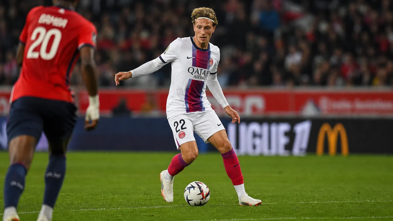 Mika Godts in een wit PSG-tenue tijdens een wedstrijdactie met de bal.