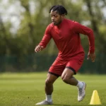 Samuel Mbangula tijdens een loopoefening op een trainingsveld in neutrale sportkleding.