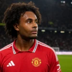 Joshua Zirkzee in rood tenue aan de rand van een voetbalveld.