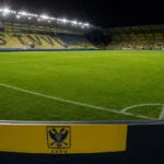 Verlicht veld in het stadion van STVV met een discreet clubbord.