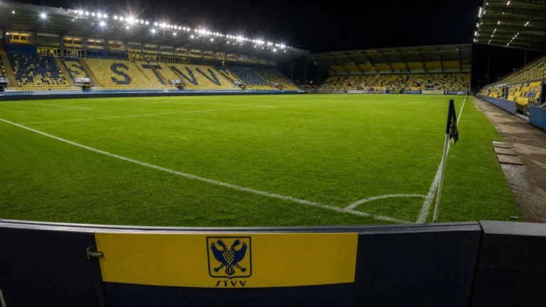 Verlicht veld in het stadion van STVV met een discreet clubbord.