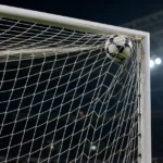 Een voetbal vliegt hoog in de hoek van het doel tijdens een wedstrijd.