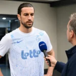 Christian Burgess spreekt in een stadionruimte voor een wedstrijd.