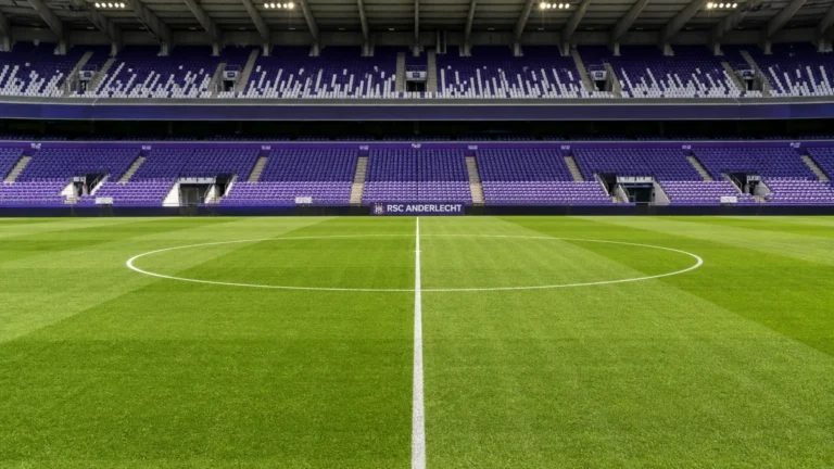 De centrale middenzone van een leeg voetbalveld in een stadion met een discreet Anderlecht-bord.
