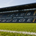 Het lege veld van Club Brugge met een discreet clubbord langs de hoofdtribune.