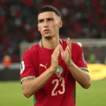 Bilal El Khannouss applaudisseert in een rood voetbalshirt op het veld.