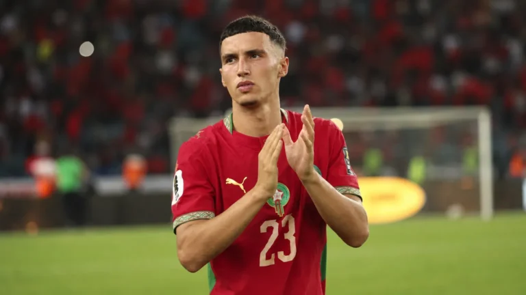 Bilal El Khannouss applaudisseert in een rood voetbalshirt op het veld.