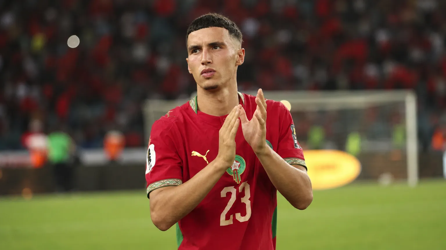Bilal El Khannouss applaudisseert in een rood voetbalshirt op het veld.